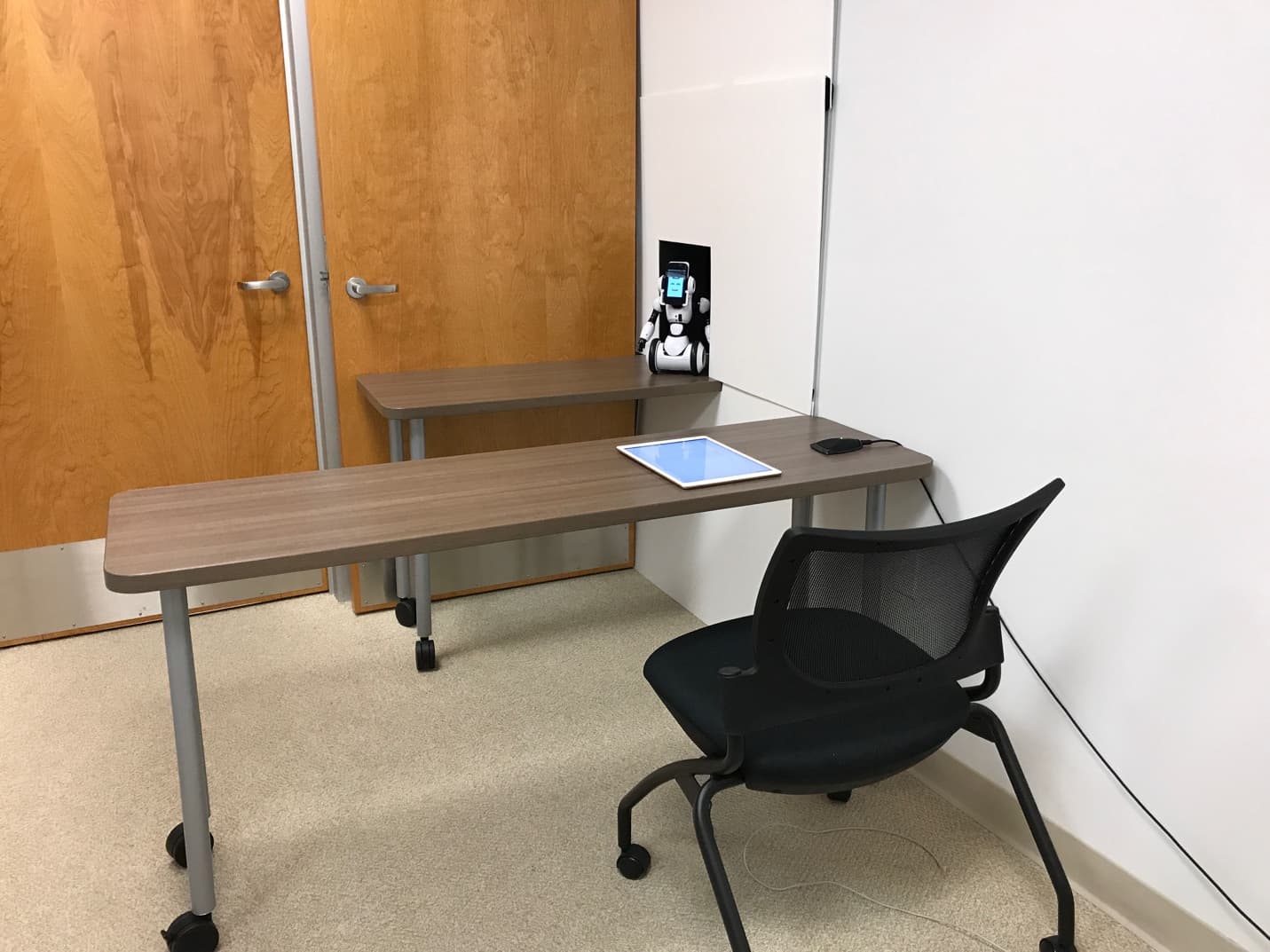 The study room with RoboMe positioned at the seated participant's eye level and a tablet used to record answers.